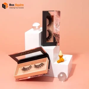 A stack of custom-printed glossy white eye lash boxes from Box Squire on a marble surface.